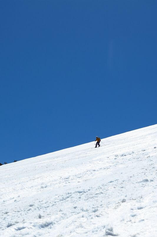華麗にテレマークターンを決めて滑り下りる山スキーヤー。