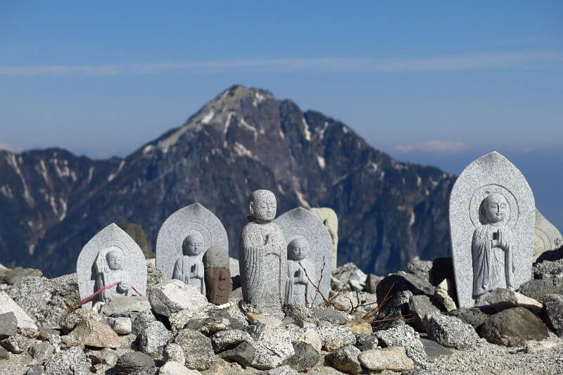 甲斐駒ヶ岳を背景に多数の石仏が並びます。